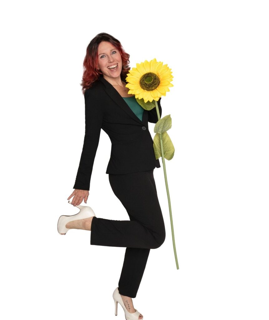 Krystal Lee Moore, London Ontario realtor, smiling in a black suit and holding a large sunflower